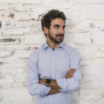 portrait of a young man in a office, in front of a white brick wall